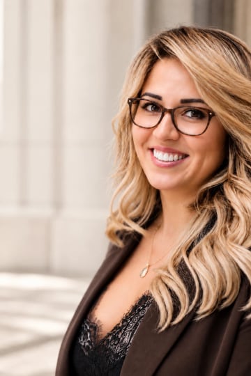 Maryam Kasimova smiling in tortoiseshell glasses and a brown blazer